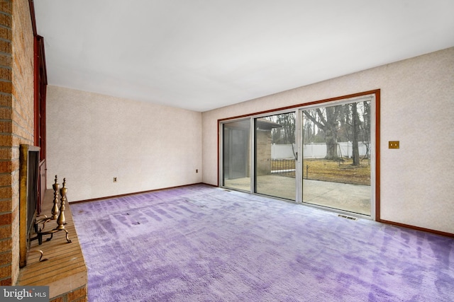 unfurnished living room with carpet floors, a fireplace, visible vents, and baseboards