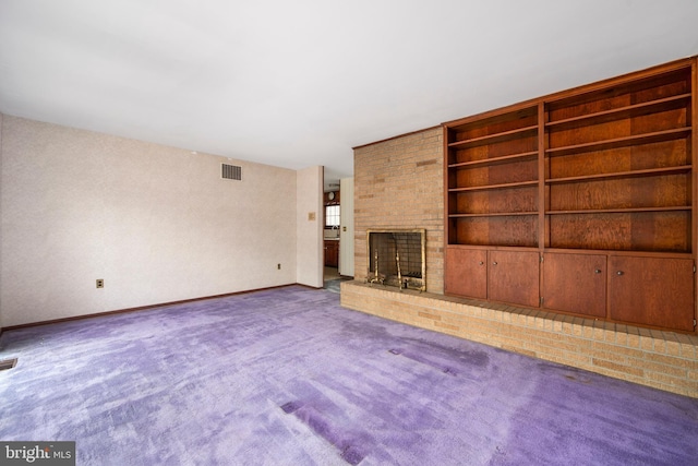 unfurnished living room with baseboards, visible vents, carpet flooring, built in shelves, and a fireplace