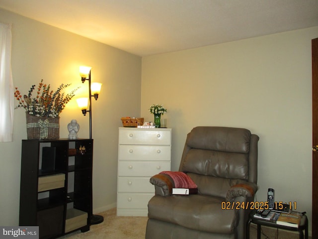 living area featuring light carpet and baseboards