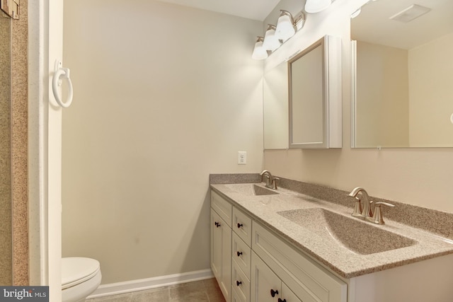 full bathroom with toilet, double vanity, baseboards, and a sink