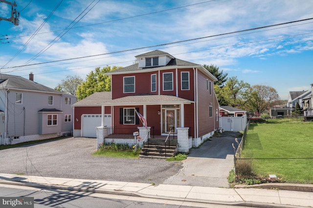 traditional style home featuring covered porch, a front lawn, fence, and aphalt driveway