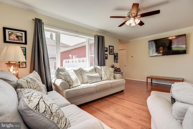 living room with light wood finished floors, ornamental molding, a ceiling fan, and baseboards