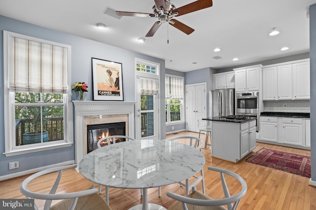 dining area with light wood-style floors, recessed lighting, baseboards, and a high end fireplace