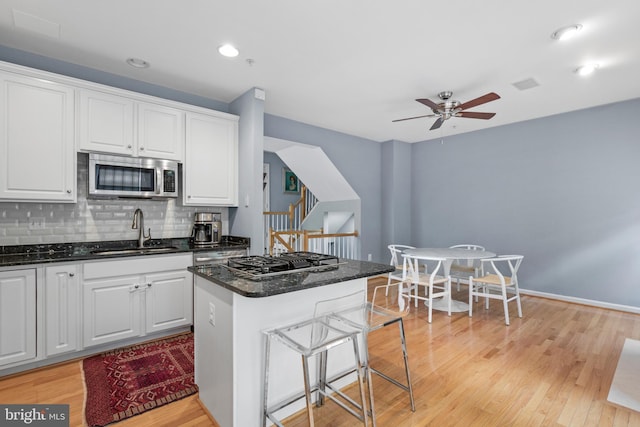 kitchen with stainless steel microwave, a center island, a sink, gas cooktop, and backsplash