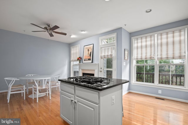 kitchen featuring light wood-type flooring, visible vents, stainless steel gas stovetop, and baseboards