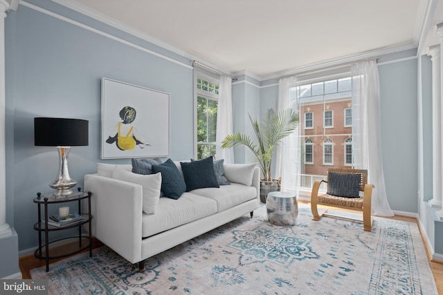 living room with baseboards, plenty of natural light, wood finished floors, and crown molding