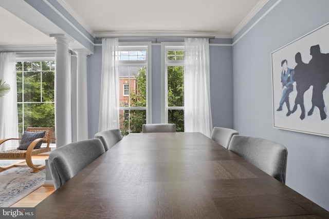 dining room featuring ornate columns, crown molding, and wood finished floors