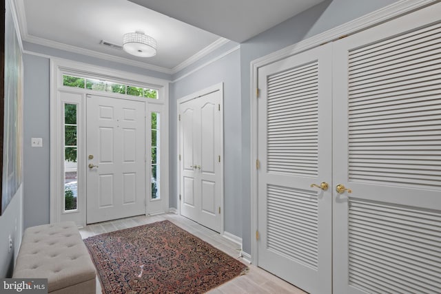 foyer entrance featuring ornamental molding, visible vents, light wood-style flooring, and baseboards