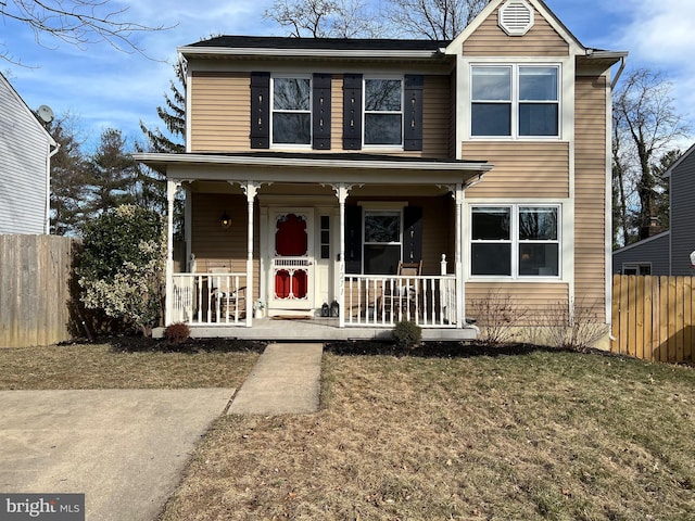 traditional-style house with a porch, a front yard, and fence