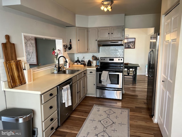 kitchen featuring dark wood-style flooring, light countertops, decorative backsplash, appliances with stainless steel finishes, and a sink