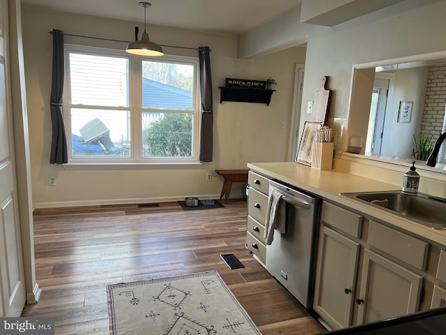 kitchen featuring dark wood finished floors, hanging light fixtures, stainless steel dishwasher, a sink, and baseboards