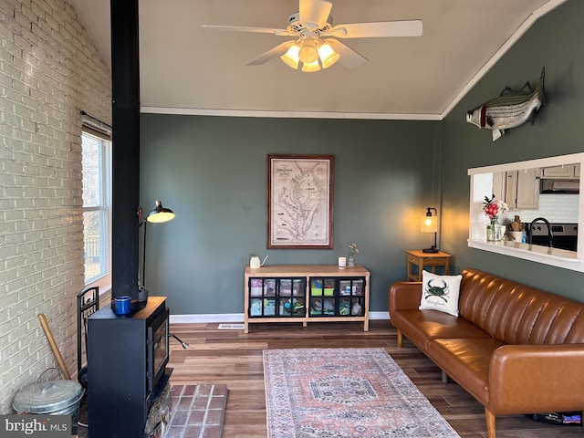 living room with lofted ceiling, wood finished floors, a wood stove, and baseboards