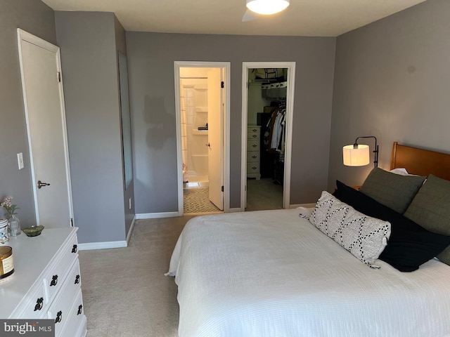 bedroom featuring carpet flooring, baseboards, a spacious closet, a closet, and ensuite bath