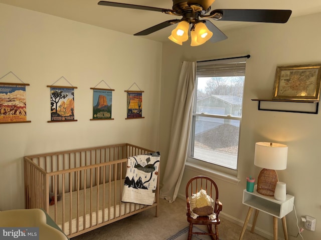 carpeted bedroom with a nursery area, ceiling fan, and baseboards