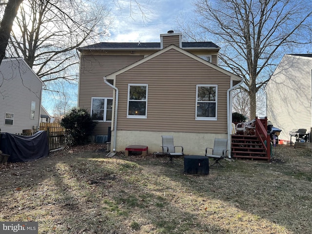 back of house with a chimney and fence