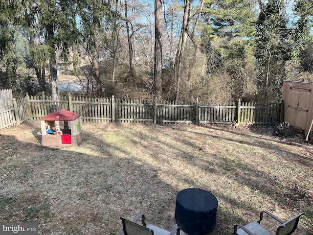 view of yard featuring a storage shed, an outdoor structure, and a fenced backyard