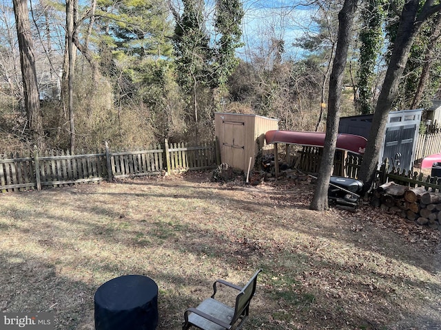 view of yard with a shed, a fenced backyard, and an outbuilding