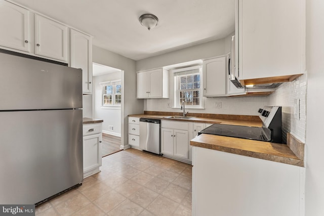 kitchen with tasteful backsplash, wood counters, appliances with stainless steel finishes, white cabinetry, and a sink