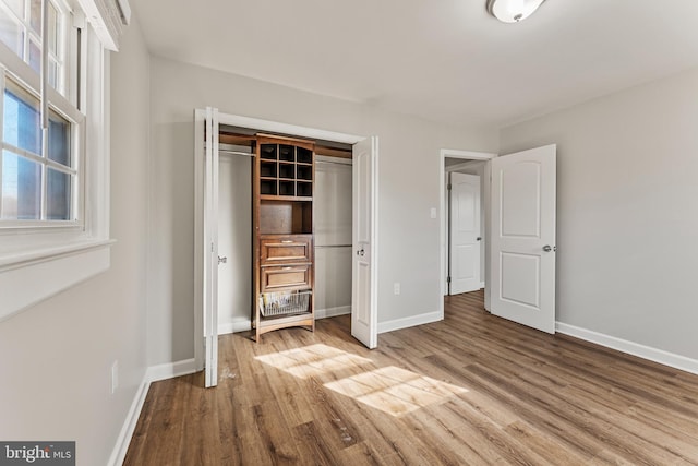 unfurnished bedroom with a closet, baseboards, and wood finished floors