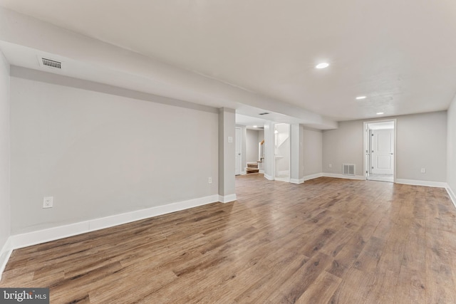 finished basement with visible vents, baseboards, and wood finished floors