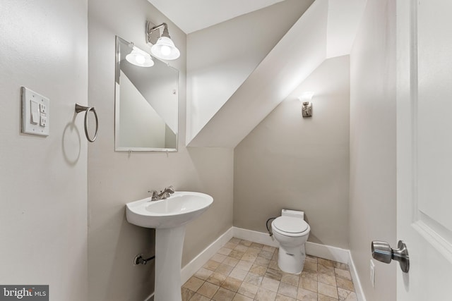 bathroom featuring baseboards, a sink, and toilet