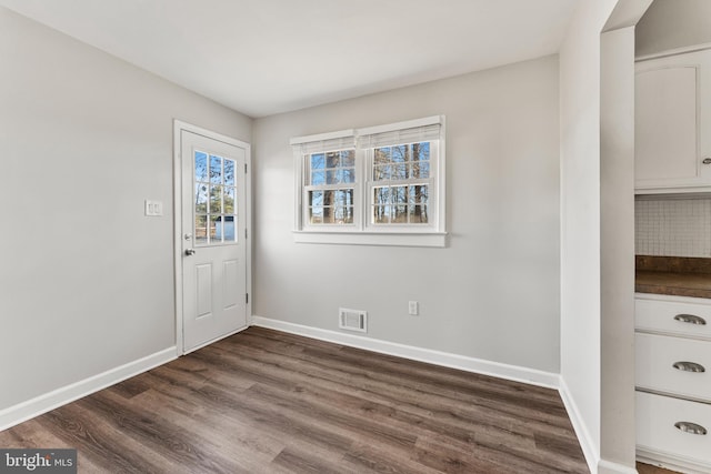 interior space featuring dark wood-type flooring, visible vents, and baseboards