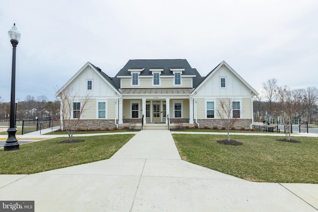 modern farmhouse style home featuring fence, stone siding, board and batten siding, a standing seam roof, and a front yard