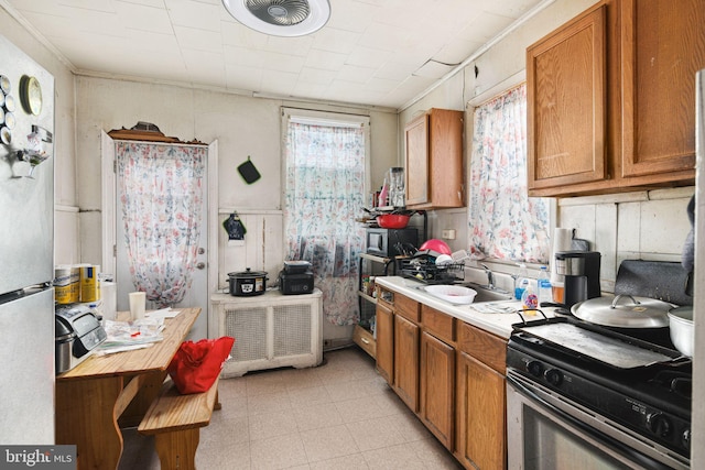 kitchen featuring appliances with stainless steel finishes, brown cabinets, a sink, and light countertops