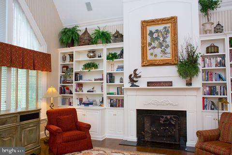 sitting room with dark wood-style flooring, a fireplace, built in features, and wallpapered walls