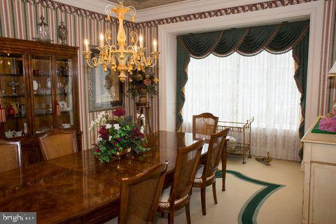 dining room featuring ornamental molding, wallpapered walls, and an inviting chandelier