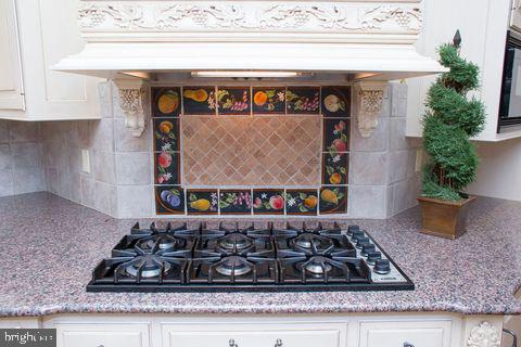 kitchen with white cabinetry, tasteful backsplash, custom range hood, and gas cooktop