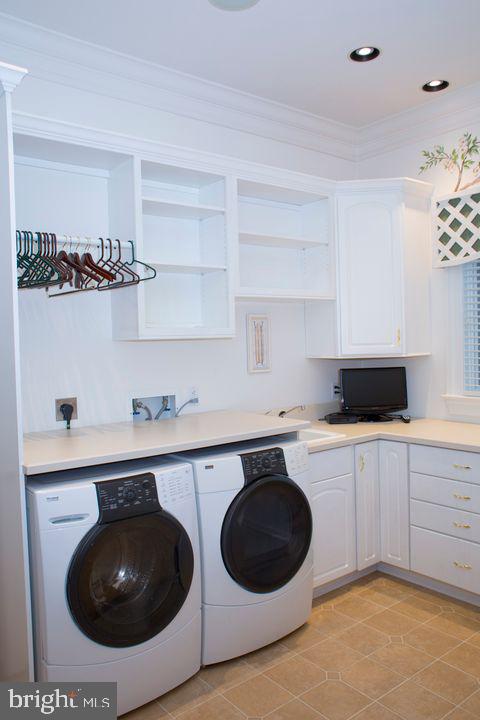 clothes washing area featuring recessed lighting, a sink, ornamental molding, independent washer and dryer, and cabinet space