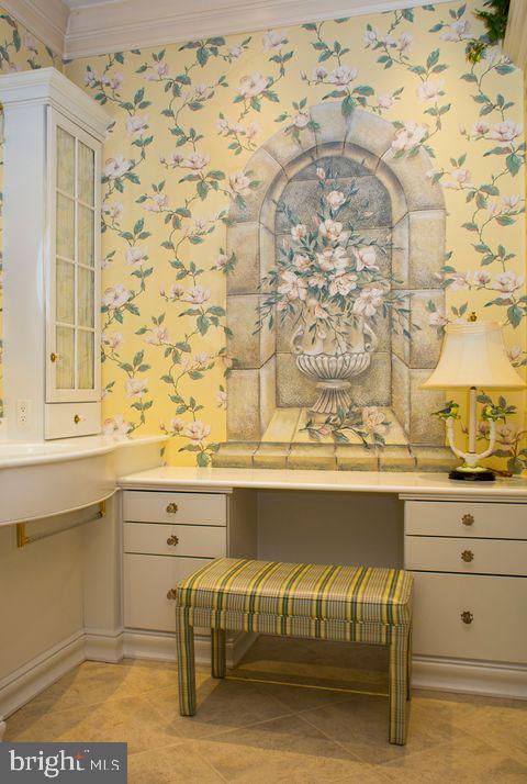 details with crown molding, built in desk, and wallpapered walls