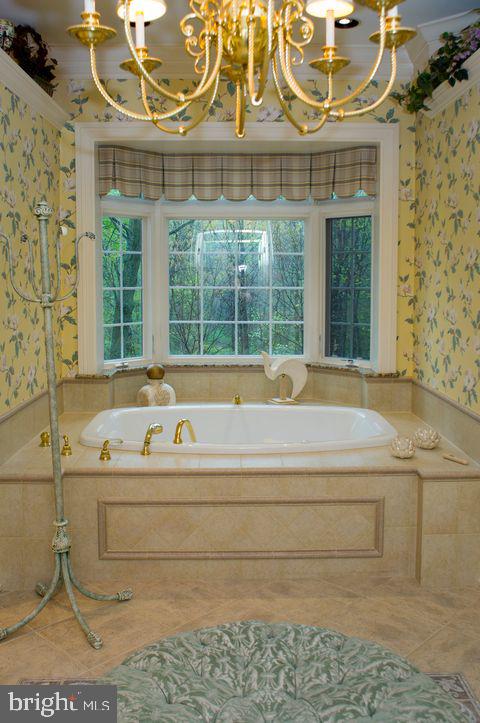 full bathroom featuring a garden tub, crown molding, an inviting chandelier, tile patterned flooring, and wallpapered walls