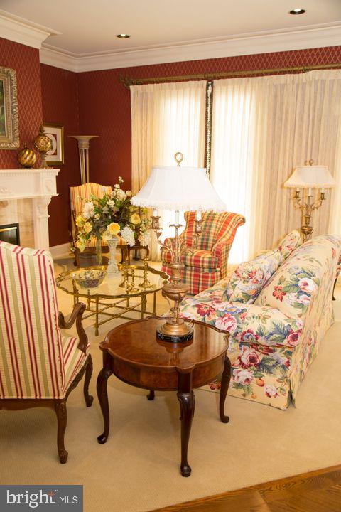 sitting room featuring ornamental molding, carpet, a tile fireplace, and wallpapered walls