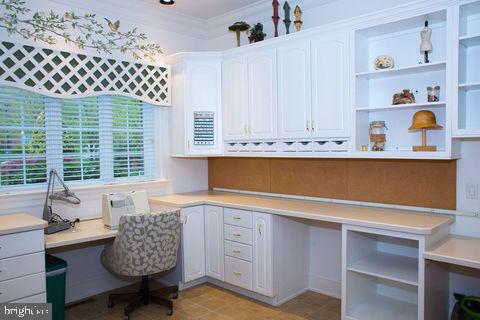 home office with ornamental molding and built in study area