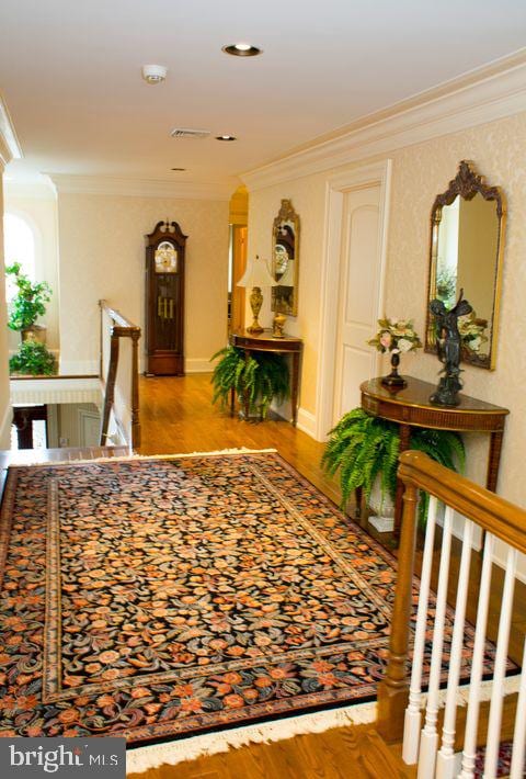 corridor with ornamental molding, wood finished floors, an upstairs landing, and baseboards