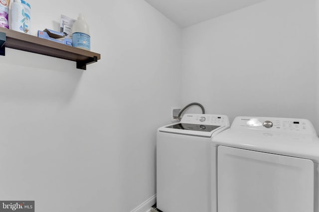 clothes washing area with laundry area, washing machine and dryer, and baseboards