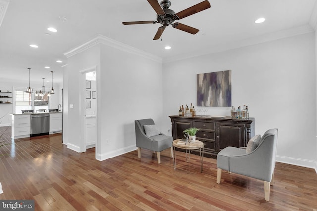 sitting room with ornamental molding, wood finished floors, and baseboards