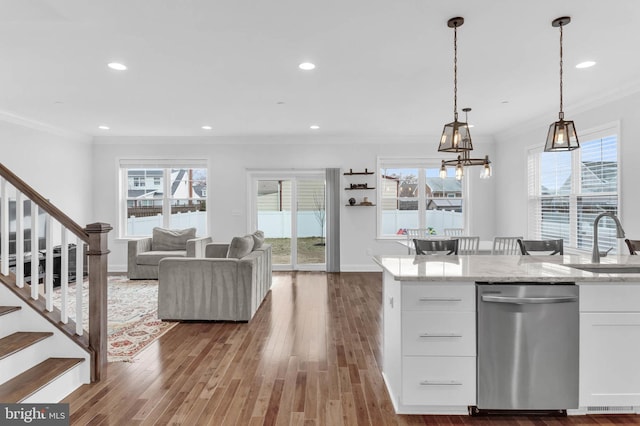 kitchen with white cabinetry, a sink, stainless steel dishwasher, and wood finished floors