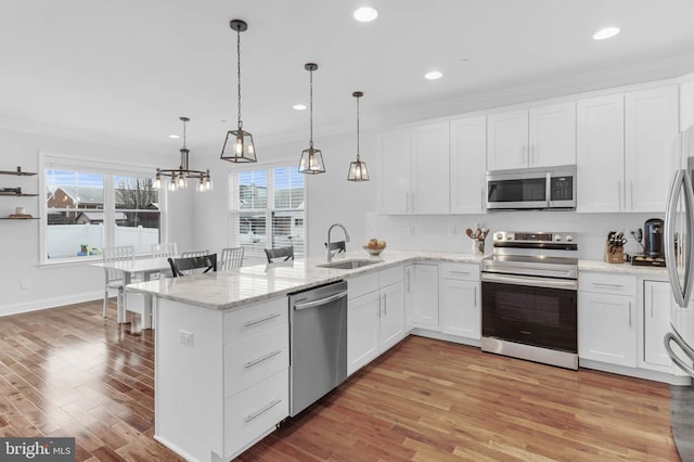 kitchen with stainless steel appliances, a peninsula, a sink, and crown molding