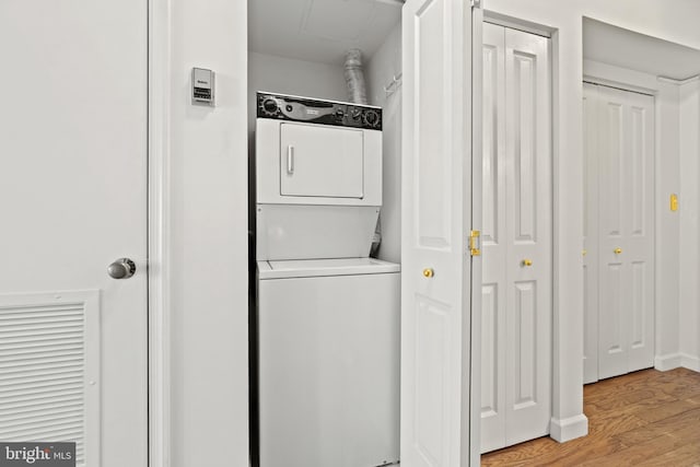 laundry area with laundry area, light wood-style flooring, and stacked washer and clothes dryer