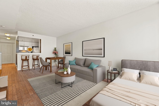 bedroom featuring light wood finished floors, a textured ceiling, and freestanding refrigerator