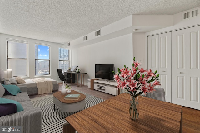 living area with wood finished floors, visible vents, and a textured ceiling