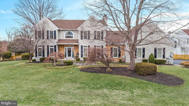 view of front facade featuring a shingled roof, a chimney, and a front yard