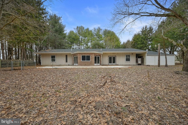 rear view of property featuring board and batten siding, a patio area, brick siding, and fence