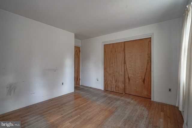 unfurnished bedroom with a closet and hardwood / wood-style floors