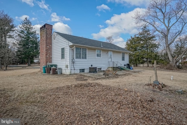 rear view of house featuring roof with shingles and a chimney