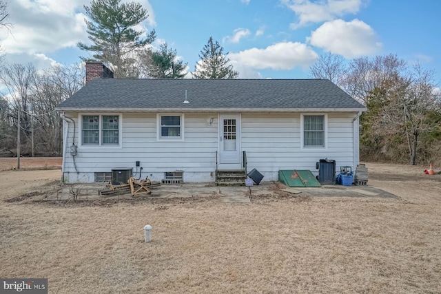 rear view of property with a shingled roof, entry steps, cooling unit, and a chimney