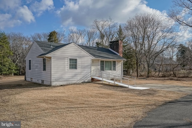 view of front of house featuring a chimney and a front lawn